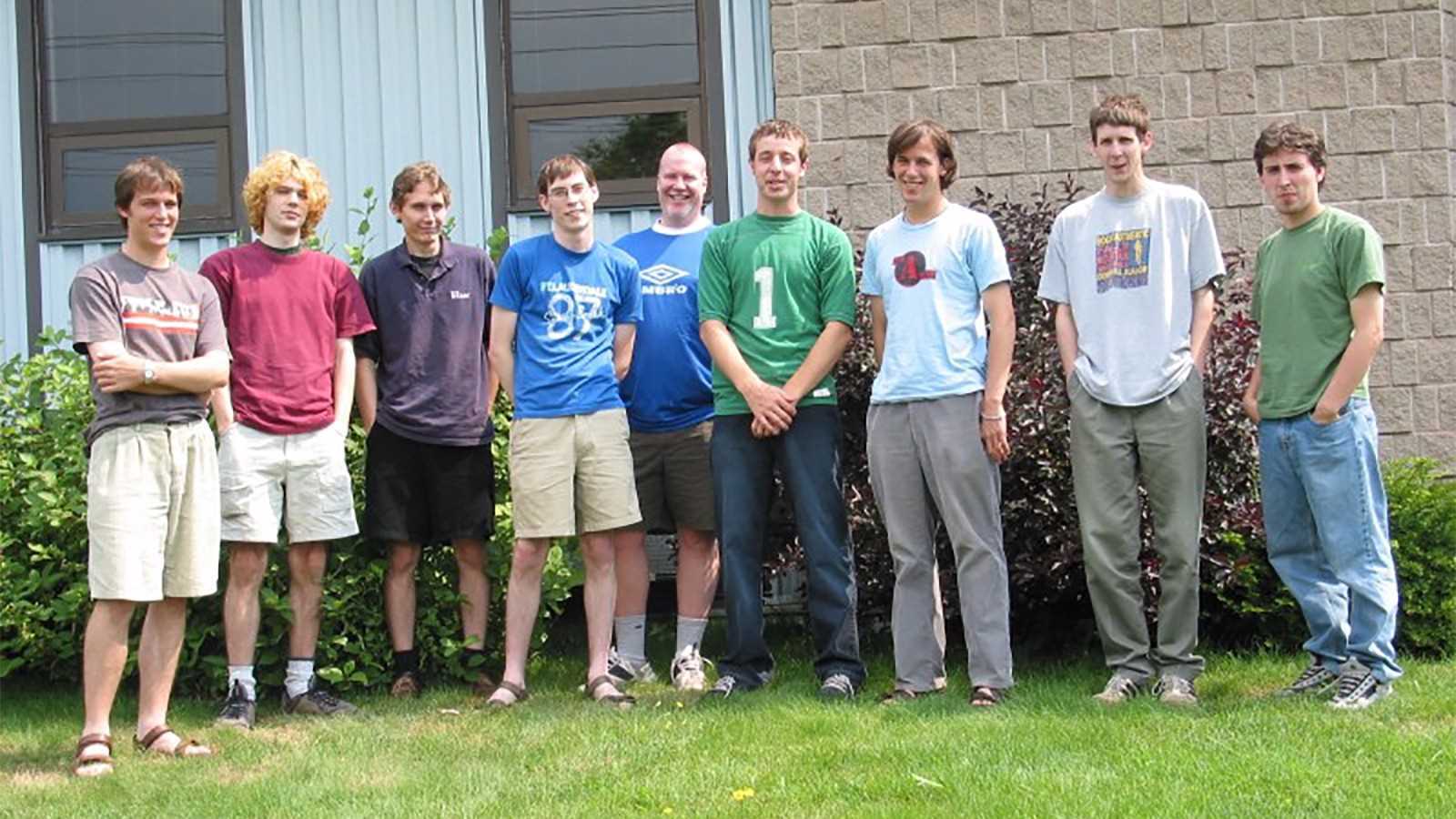 Group of young men standing awkwardly on an office lawn