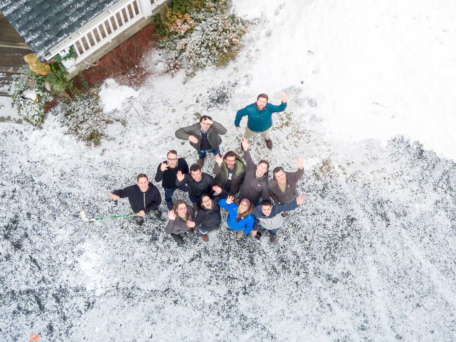 Group of people looking up and waving at drone camera