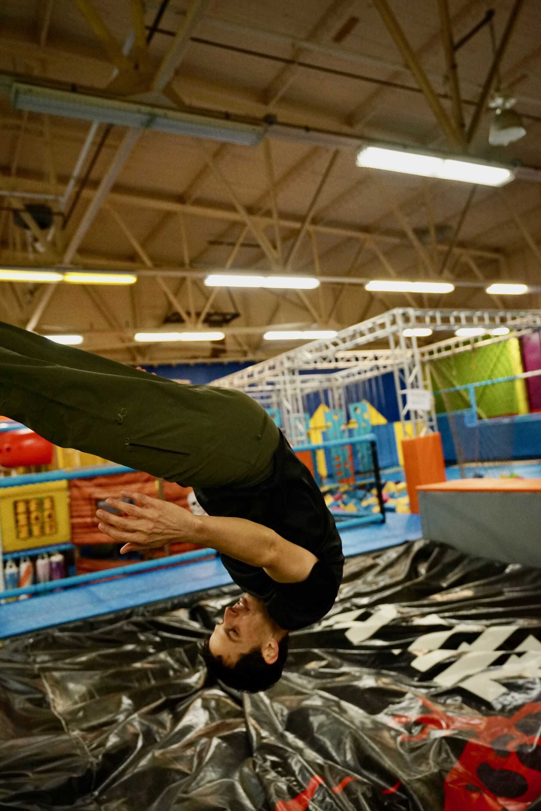 Man upside down in air over soft mat