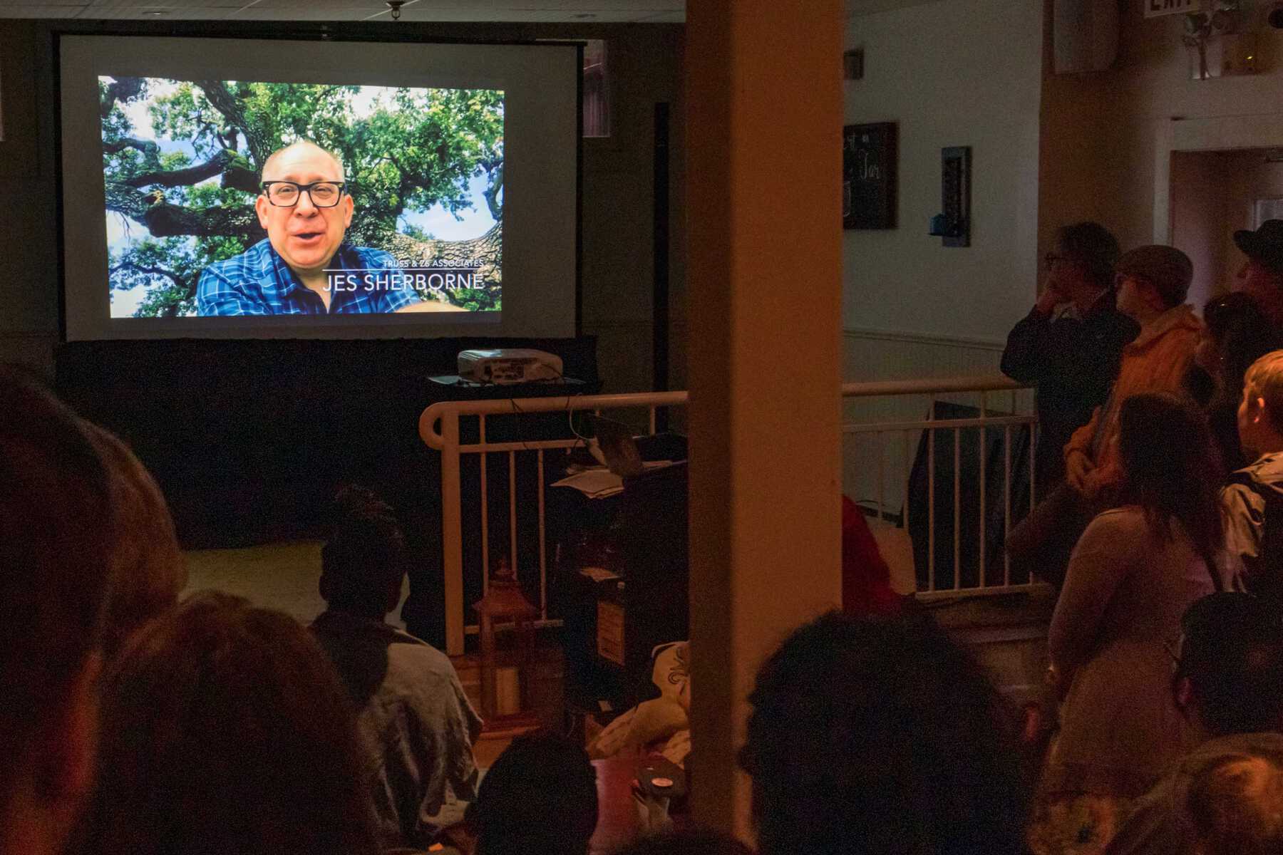 People watching video on projector screen of man speaking