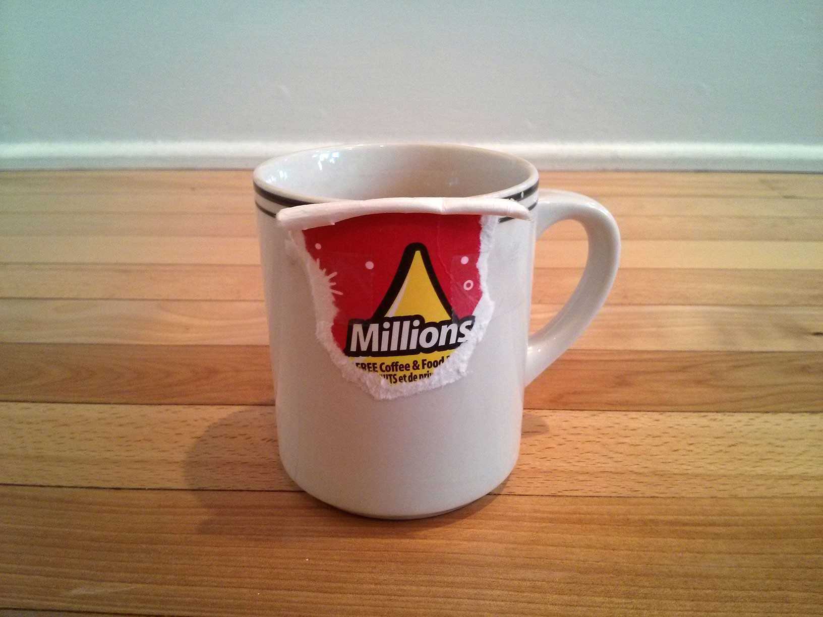 White porcelain coffee mug with torn Tim Horton's Roll-Up-The-Rim tab on the edge