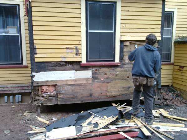 Man removing siding from house