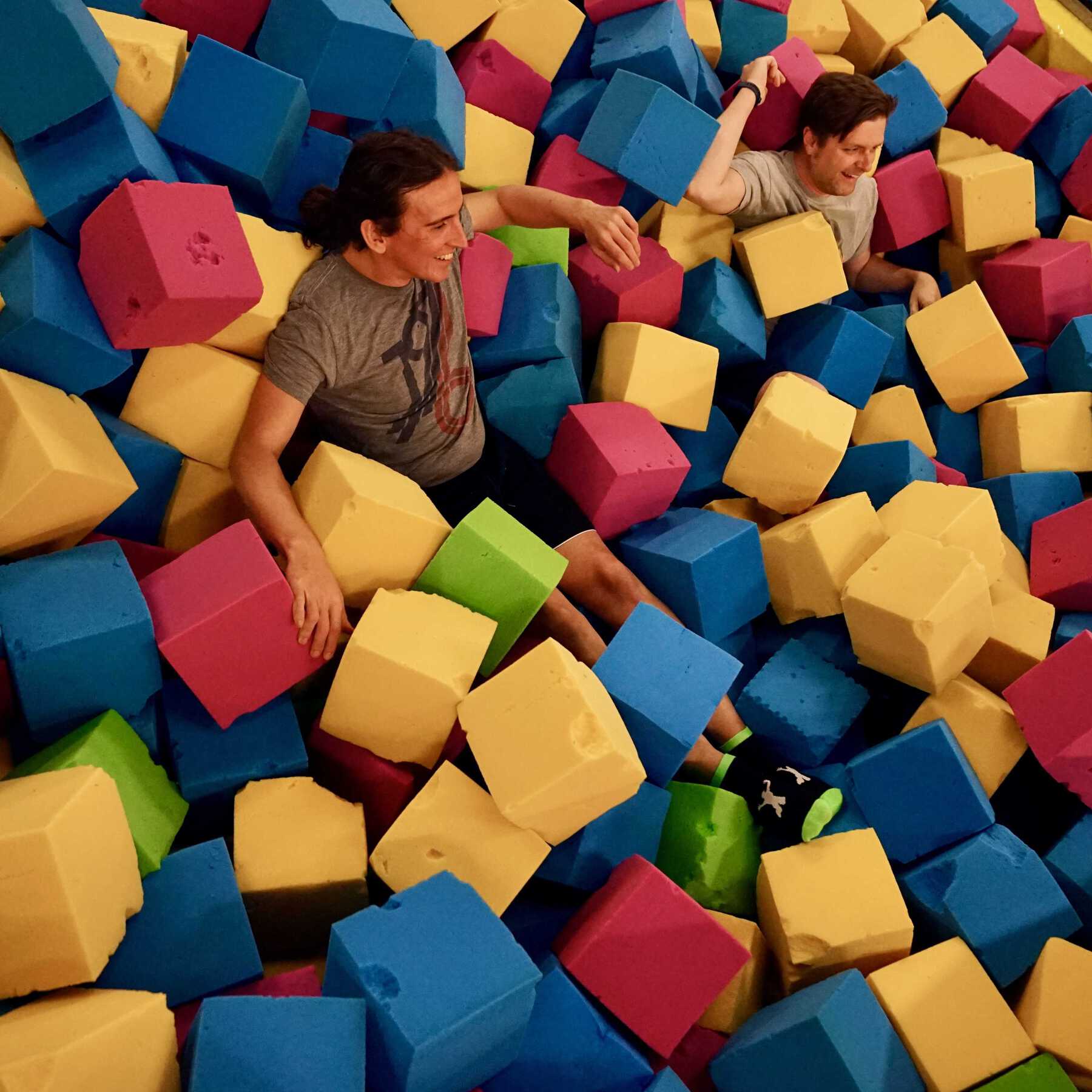 People smiling in pile of foam cubes
